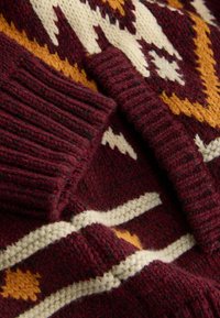 Strickpullover in dunklem Burgunderrot mit geometrischen Mustern in Creme, Gelb und Orange. Verfügt über gerippte Bündchen und strukturierte Stoffe.