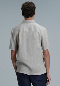 Lichtbeige shirt met korte mouwen, gemaakt van een gestructureerde stof. Comfortabele pasvorm met een klassieke kraag en subtiele stikdetails aan de achterkant.