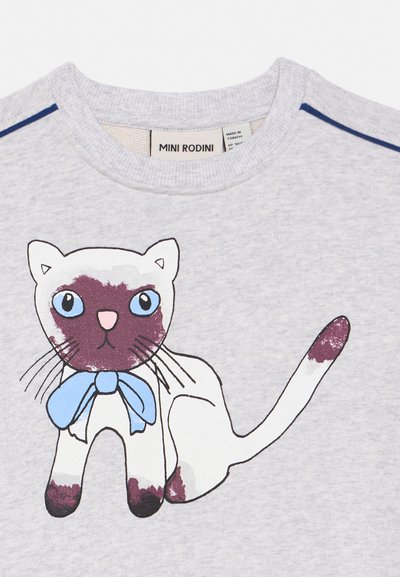 Siva majica z risankasto belo mačko s temnimi vzorci, modrimi očmi, roza nosom in modrim lokom okoli vratu.