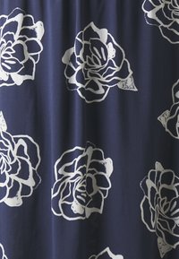 Marineblått stoff med hvite roseprint, med en glatt tekstur og blomsterdesign. Rosene har detaljerte kronblader og kraftige konturer.