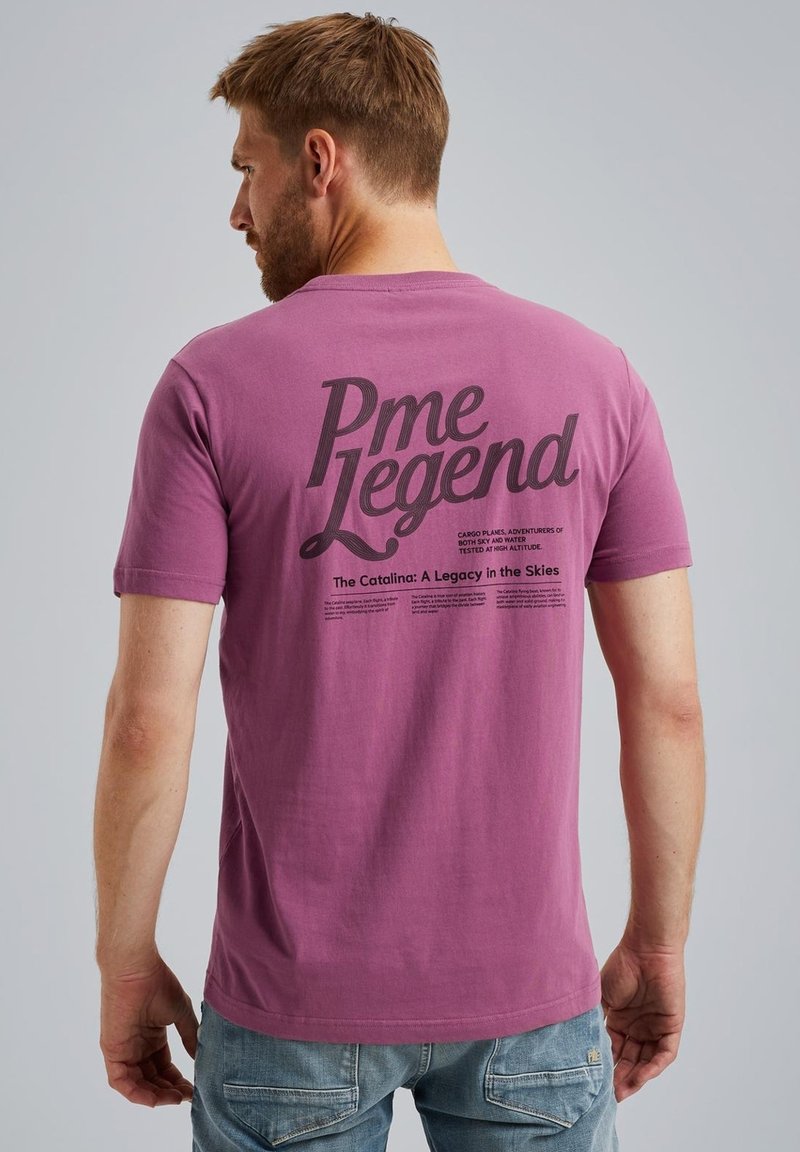 Fialové bavlněné tričko s velkým černým potiskem "Pme Legend" na zadní straně, s dalším textem pod ním. Krátké rukávy a kulatý výstřih.