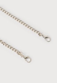 Δύο ασημένιες προεκτάσεις αλυσίδας με κλειδαριές σε σχήμα παλαμάκια αστακού σε λευκό φόντο, τοποθετημένες διαγώνια και μερικώς αποχωρισμένες.