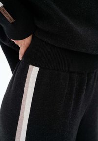 Czarna, teksturowana tkanina o miękkim wykończeniu ma kontrastujący kremowy i beżowy pasek po boku. Żebrowany pas dla lepszego dopasowania.