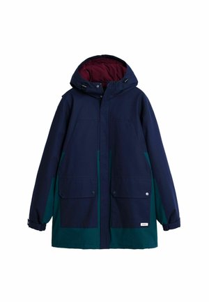 Navy blue and green waterproof jacket with a hood, featuring two large front pockets and a maroon inner lining. Adjustable cuffs included.