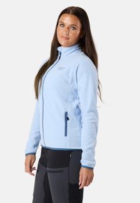 Hellblaues Fleece-Jacke mit durchgehendem Reißverschluss, hohem Kragen und zwei Reißverschlusstaschen. Mit dunkelblauen Akzenten und einem dezenten Logo.