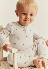 Ensemble de pyjama en coton blanc côtelé pour tout-petits, avec de petits motifs floraux, doté d'un col à boutons et de renforts aux genoux.