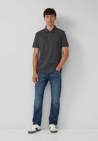 Donkergrijs polo t-shirt met korte mouwen, gecombineerd met lichtblauwe jeans en witte sneakers. Recht gesneden ontwerp met een klassieke kraag.
