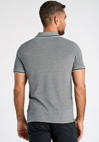 Grå polotröja med en texturerad yta, med en kontrasterande krage och ärmkanter i marinblått. Tröjan har en slim fit och korta ärmar.