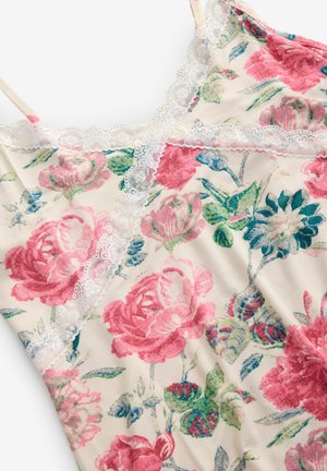 Camisola floreale in crema, con un vivace motivo di rose rosa e verdi. Il pizzo lungo il collo e le spalline aggiunge un tocco delicato.