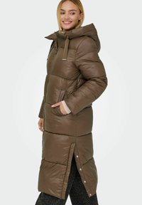 Hnědý polstrovaný dlouhý kabát s kapucí, který má postranní kapsy, plný přední zip a patentky na lemu pro nastavitelnou velikost.