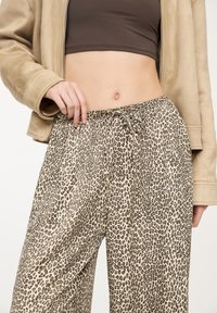 Pantalon large à imprimé léopard en tissu doux, doté d'une taille élastique avec cordon de serrage pour un ajustement réglable.