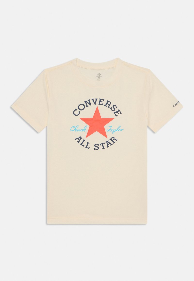 Camiseta de algodón color crema con un gráfico central de estrella roja, texto negro que dice "CONVERSE ALL STAR" y acentos azules en el diseño.