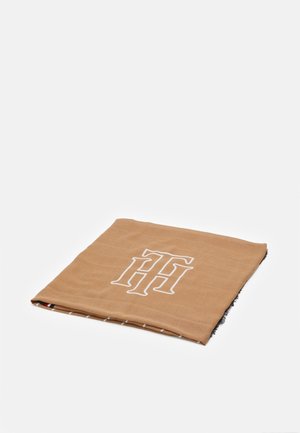 Écharpe brun clair pliée avec de grandes lettres blanches stylisées en double H sur le dessus, montrant une petite section à carreaux noir et blanc en dessous.