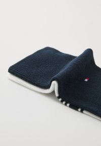 Chaussette en coton bleu marine avec une texture côtelée, ornée d'un revers blanc et de accents rouge et bleu au niveau des orteils et du talon.