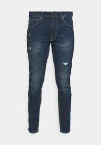 Jeans de corte ajustado en azul oscuro, elaborados en denim, con parches desgastados, un ligero desvanecimiento y diseño clásico de cinco bolsillos con herrajes de metal.