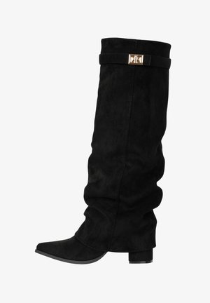 Bota alta hasta la rodilla de gamuza negra con caña caída, tacón bajo de bloque, punta puntiaguda y una correa decorativa con hebilla dorada cerca de la parte superior.