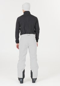 Zwarte lang mouwtop gecombineerd met lichtgrijze sneeuwbroek, met een aansluitend design, gladde textuur en zwarte manchetten bij de enkels.