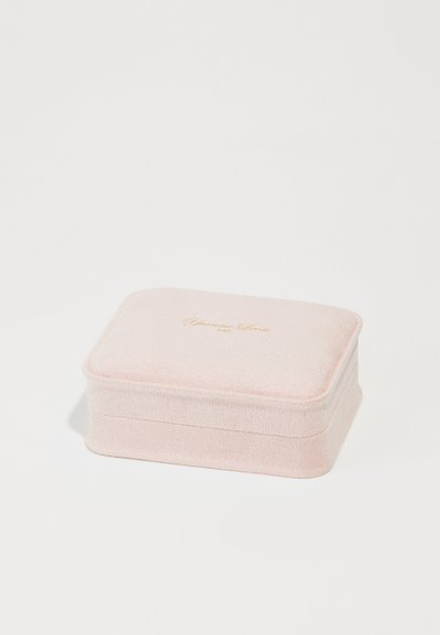 Rosa sammetsjewelrybox med rektangulär form, som har en subtil textur och guldtexten "Yvonne Leon Paris" på locket.