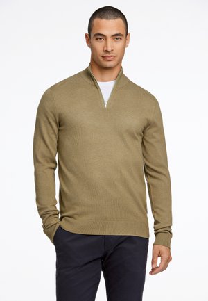 Maglione pullover verde oliva realizzato in un materiale a maglia testurizzato, caratterizzato da un colletto con cerniera e maniche lunghe, abbinato a pantaloni scuri.