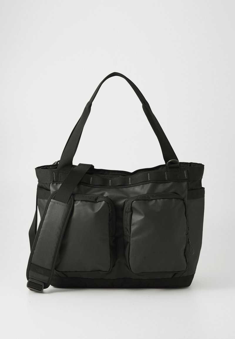 Bolso tote negro hecho de material duradero, con dos bolsillos frontales, correa de hombro ajustable y abertura superior con cremallera.