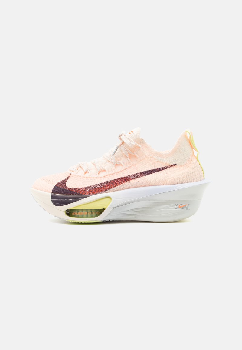 Ανοιχτό ροζ αθλητικό παπούτσι Nike με μεγάλο πορτοκαλο-μαύρο swoosh, παχιά λευκή σόλα με ορατό αερόσακο και κίτρινη θηλιά στη φτέρνα.