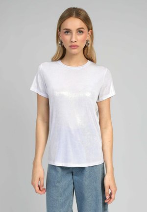 T-shirt blanche à manches courtes en tissu brillant et texturé avec un col rond, associée à un pantalon en denim bleu ample.