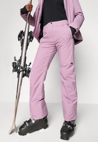 Lichtpaarse skibroek van waterproof materiaal met een rechte snit, voorzien van zijzakken en een logoprint. Zwarte skischoenen inbegrepen.