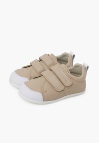 Scarpe in pelle beige con punte e suole in gomma bianca. Presentano due cinturini regolabili in Velcro. Texture liscia con accenti di cuciture minime.
