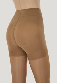 Bruna genomskinliga strumpbyxor med hög midja, halvgenomskinlig textur och en slät finish. Har förstärkta band vid lårområdet.