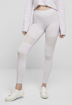 Leggings violets clairs avec des accents en maille de différentes tailles. Texture lisse, taille haute, associés à des baskets blanches.