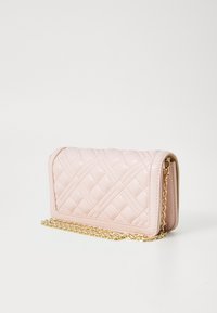 Geantă crossbody din piele ecologică roz, matlasată, cu o curea din lanț aurie, de formă rectangulară și cu un model de cusături diagonale.