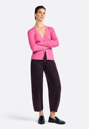 Cardigan ajusté rose à côtes avec des manches longues et des boutons, associé à un pantalon baggy violet foncé et des mocassins noirs. Design simple et moderne.