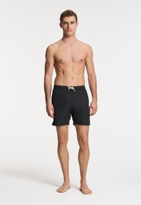 Schwarze Badehose mit elastischem Bund und Kordelzugdetails, ausgestattet mit geradem Schnitt und leichtem Stoff.