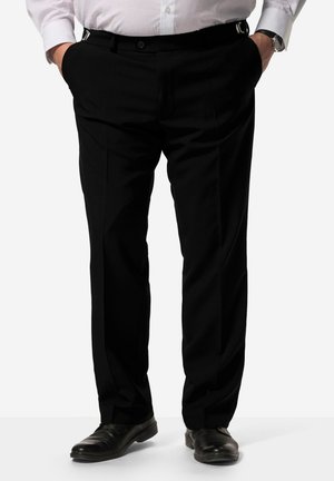 Pantaloni neri eleganti con vestibilità su misura, fronte plissettato e tasche laterali. Dotati di cinturini regolabili e scarpe nere eleganti.
