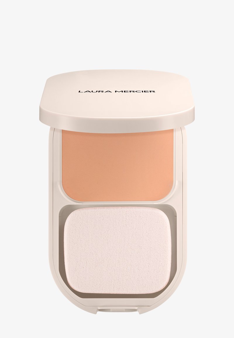 Base en polvo compacta de color beige con esponja aplicadora en una caja de color crema etiquetada "LAURA MERCIER" en la tapa.