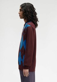 Maglione bordeaux con motivi a diamante blu, maniche lunghe e colletto. Tessuto morbido con una vestibilità rilassata. Design semplice con dettagli minimi.