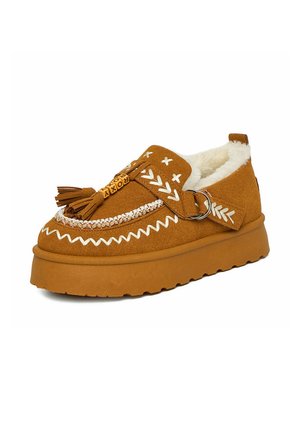 Brauner Wildleder-Slipper mit weißen Nähten, Quasten, dekorativem Riemen mit Ring und weißem, flauschigem Innenfutter.