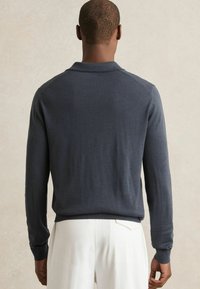 Tummanharmaa pitkähiha pullover, jossa on kaulus, valmistettu sileästä ja kevyestä kankaasta. Varustettu ribbaatuilla hihoilla ja helmalla, yksinkertainen muotoilu.