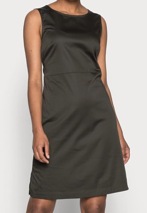 Czarna sukienka bez rękawów o satynowym wykończeniu, noszona przez osobę, długość do kolan, z okrągłym dekoltem i gładką, lekko dopasowaną sylwetką.