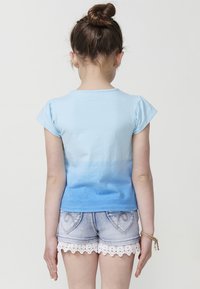 Svjetloplavi kratki rukav T-shirt s ombre dizajnom, u kombinaciji s traper kratkim hlačama s čipkastim obrubom i džepovima u obliku srca.