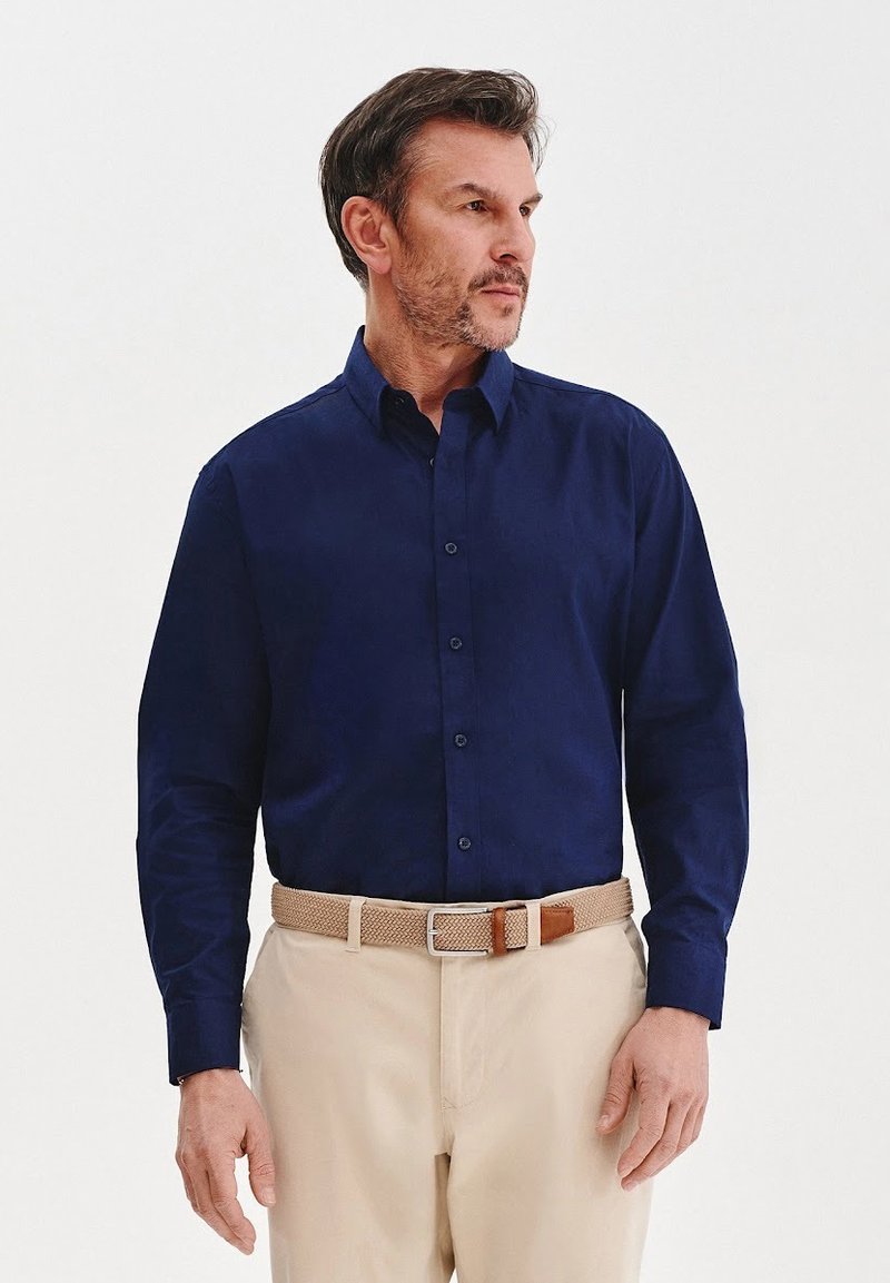 Granatowa, długosleeve koszula z guzikami z przodu, wykonana z bawełny, w połączeniu z beżowymi spodniami i plecionym paskiem z skórzanymi akcentami.
