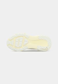 Suola bianca di una sneaker con un design testurizzato, sezioni segmentate e un accento giallo. La suola presenta un motivo di piccole grip.