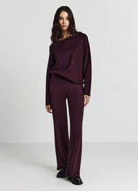 Burgunderfarbenes Lounge-Set mit locker sitzendem Langarmoberteil und weit geschnittenen Hosen, hergestellt aus weichem Stoff, mit geripptem Halsausschnitt und entspannter Silhouette.