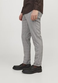 Grå rutiga byxor med subtil textur, smal passform och sidofickor, parat med svarta loafers med kraftig sula.