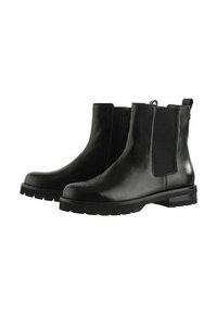 Une paire de bottines noires en cuir avec des panneaux élastiques sur les côtés, des fermetures éclair, des détails en brogue sur les orteils et des semelles en caoutchouc épaisses.