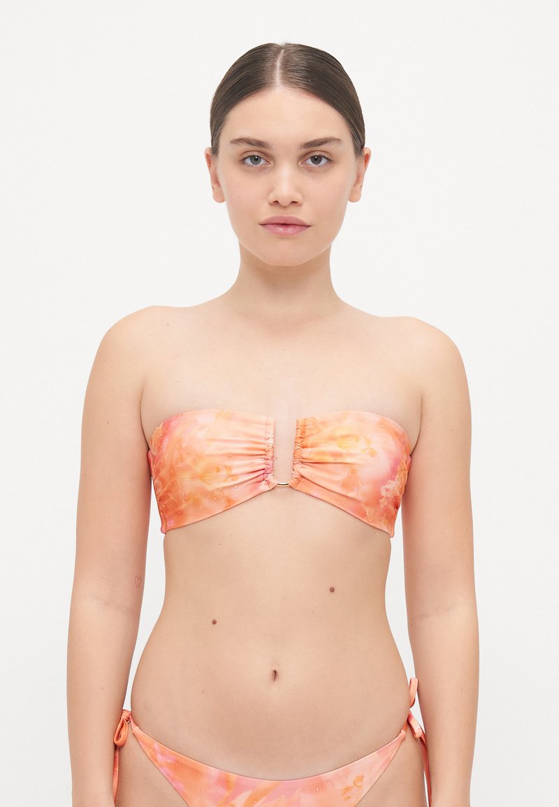 Strapless bikini top in soft, floral-patterned fabric featuring shades of pink and orange, with ruching details and a central gold clasp.