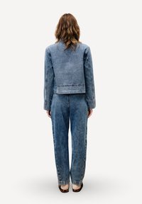 Denimjack en high-waisted broek in lichtblauw, met een cropped ontwerp, zichtbare stiksels en wijde pijpen. Vierkant uitgesneden kraag en rug.