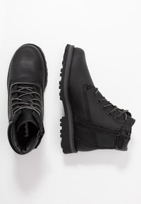 Botas de cuero negro con cuello acolchado, parte delantera con cordones y detalle de cremallera en el lateral. Suela de goma resistente con agarre texturizado, diseñada para la durabilidad.