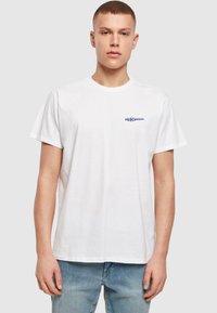 Hvid bomuld t-shirt med rund hals og korte ærmer. Foran vises blå tekst, "DIE FLIPPERS," i et simpelt, fedt font.