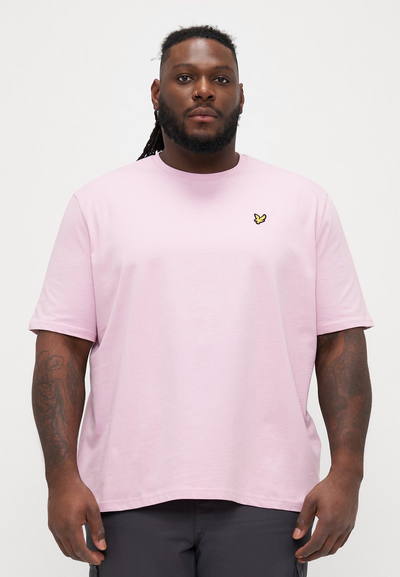 Tricou scurt cu mânecă, de culoare roz deschis, cu guler rotund, croială lejeră, prezintă un mic logo brodat cu fluture galben în partea stângă a pieptului.
